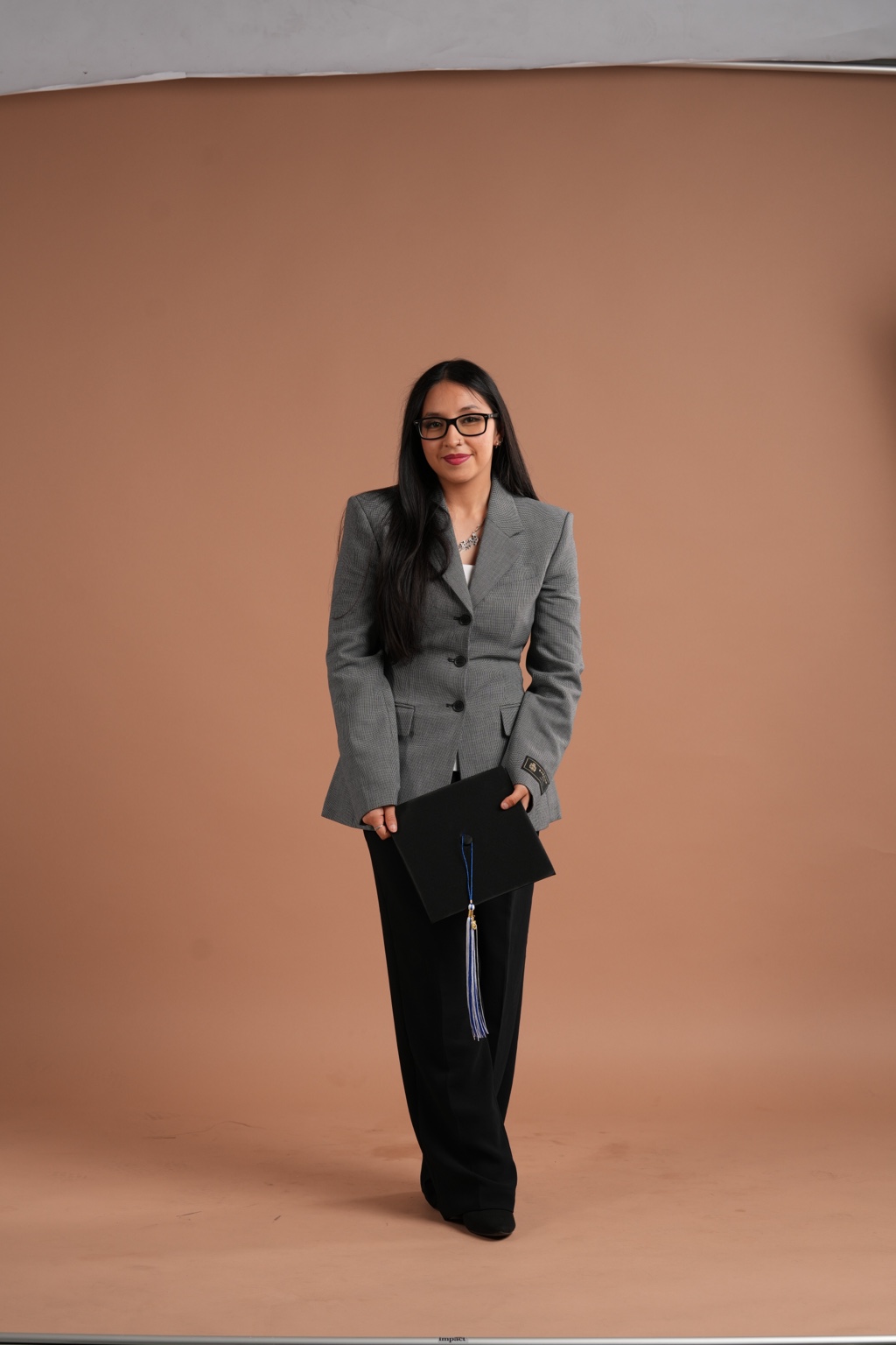 Brittany Garcia Peralta wearing a gray blazer and holding a graduation cap